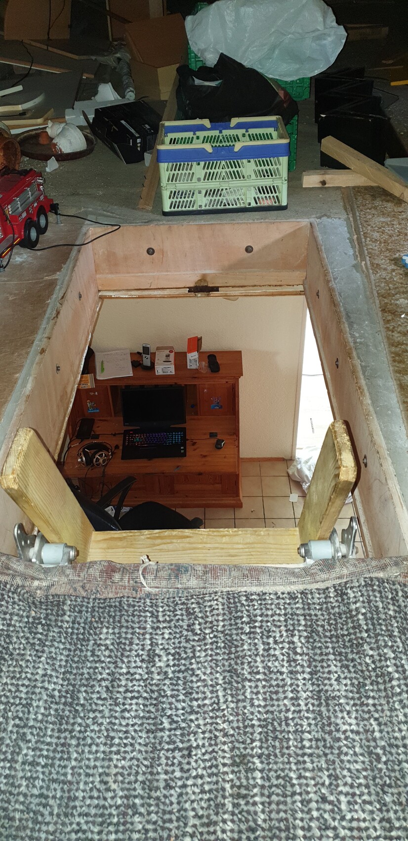 Open floor hatch leading to basement room with desk, computer, monitor, keyboard; chaos above.
