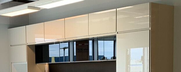 Modern white high-gloss wall unit in an office with a black open compartment.