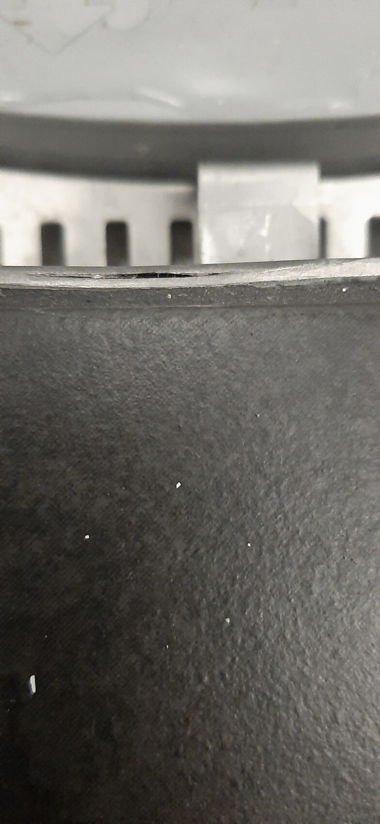 Close-up of a black surface with a grey edge and ventilation slots behind.