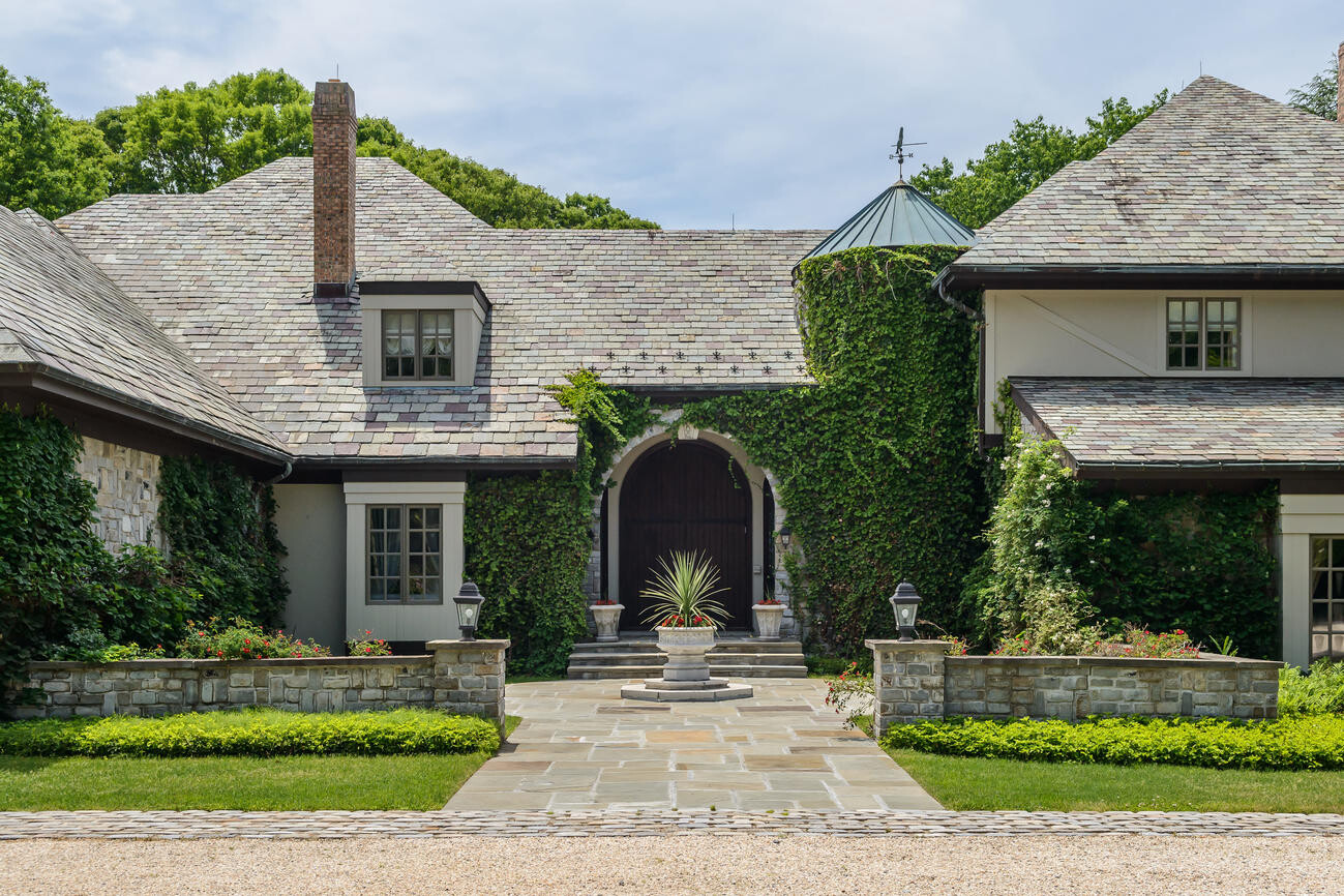 Well-maintained stone villa with archway, ivy on walls, central planting bed, and gravel path.