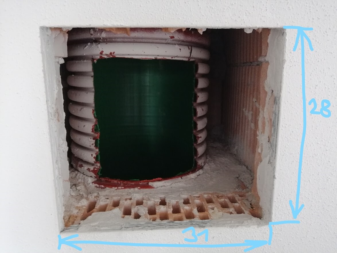 Open wall opening with green cylindrical core and surrounding white spiral (construction site).