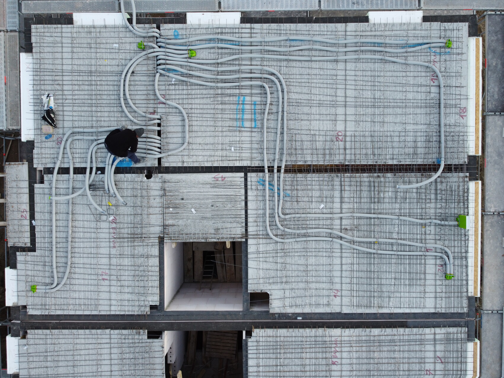 Bird's-eye view: Construction worker laying pipes on a concrete construction site with reinforcement.