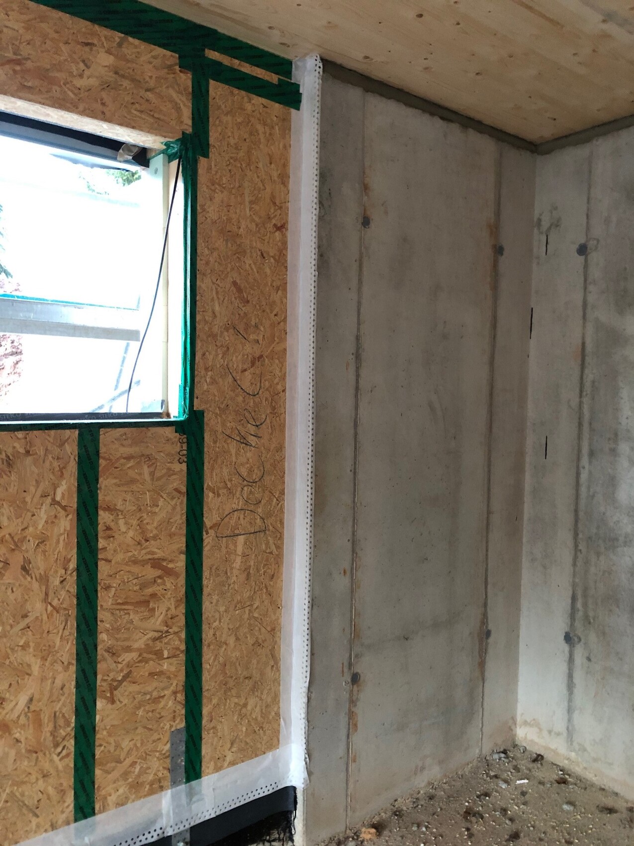 Interior view of a shell construction: concrete wall on the right, OSB cladding on the left, window opening.