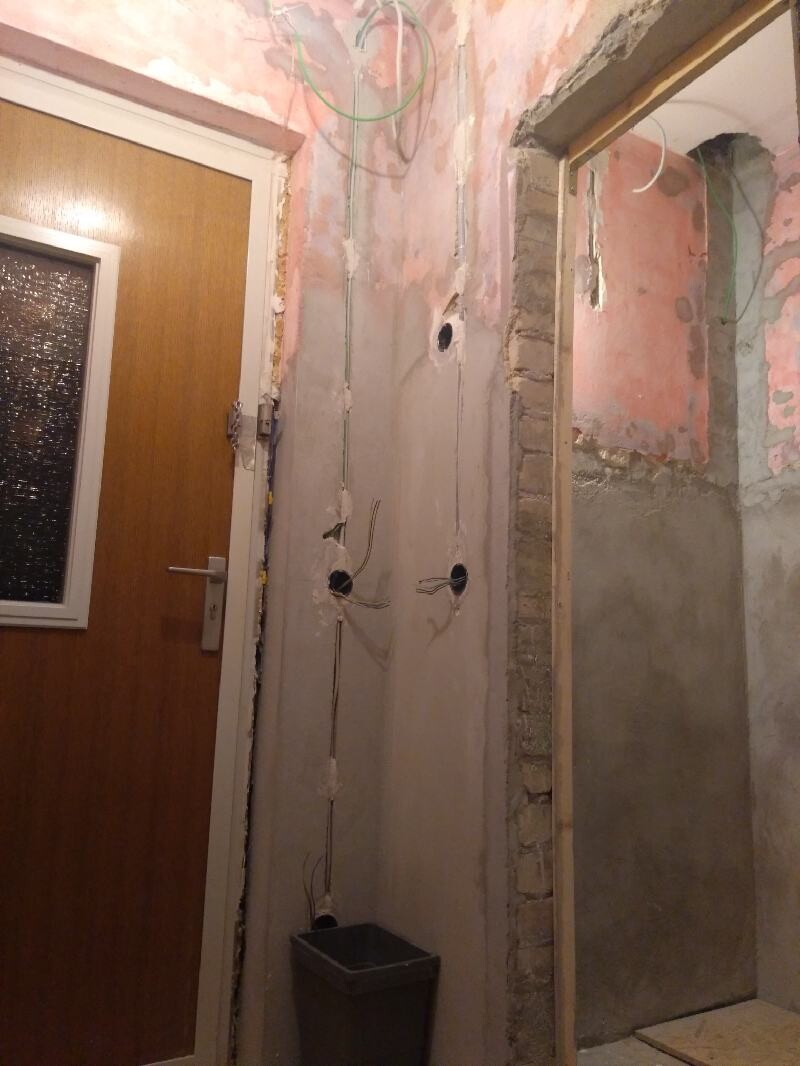 Corridor/renovation room with exposed cables, shell construction wall, and bucket next to the door.