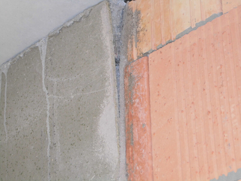 Rough construction corner: visible concrete and brick wall with traces of mortar