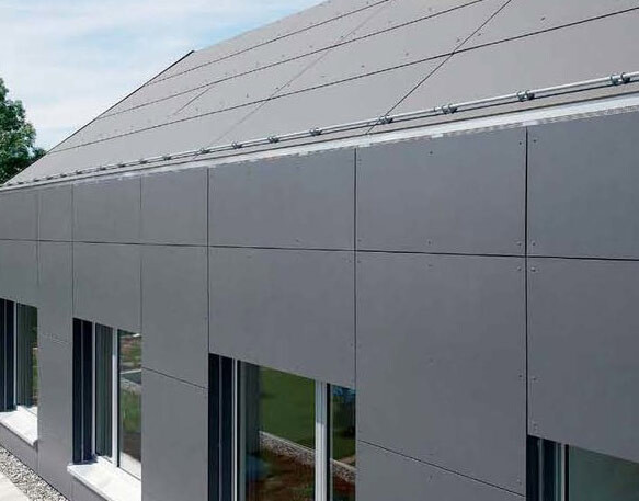 Modern gray facade cladding with panels, windows on the ground floor, and a sloped roof.