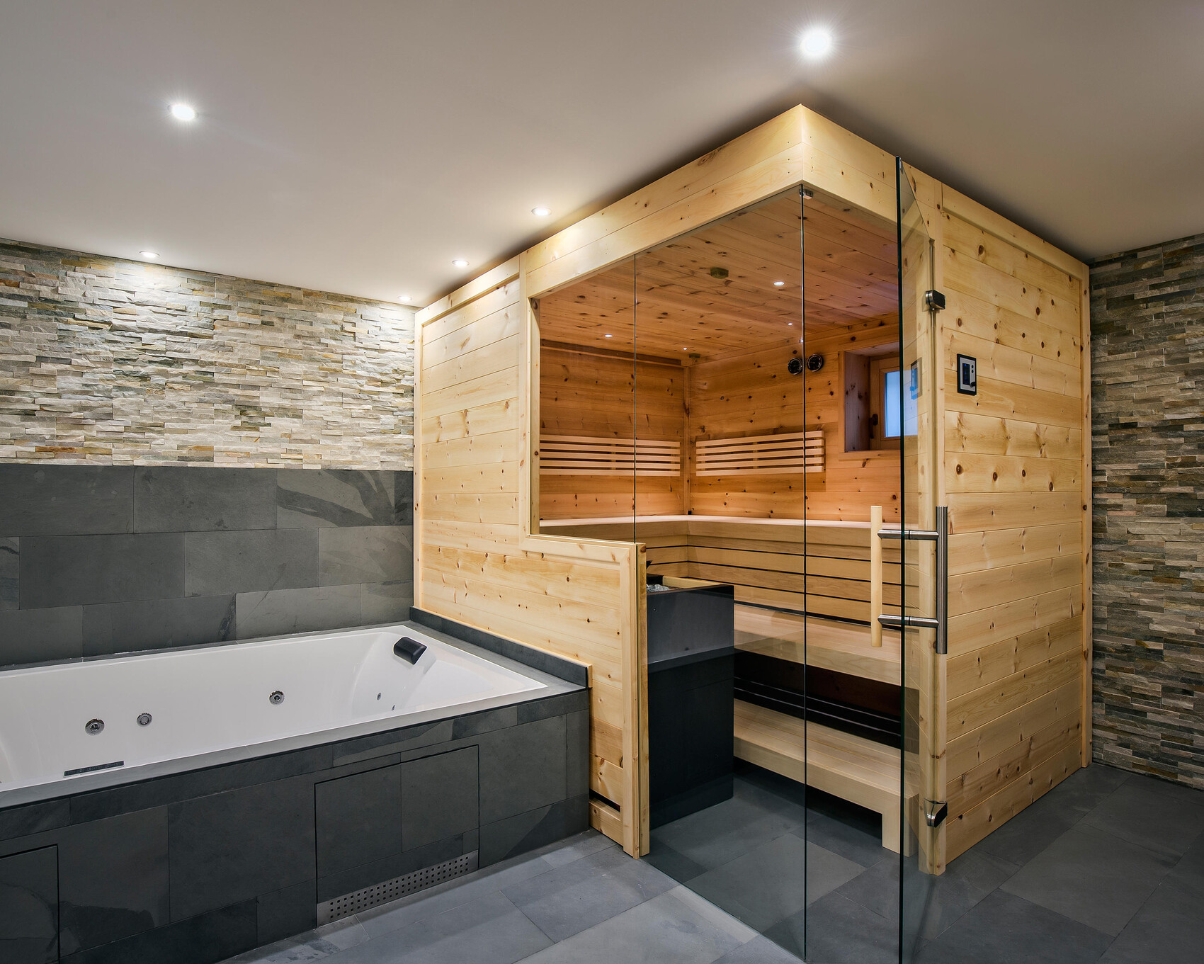 Large bathtub next to a wooden sauna with a glass front in a modern wellness oasis.