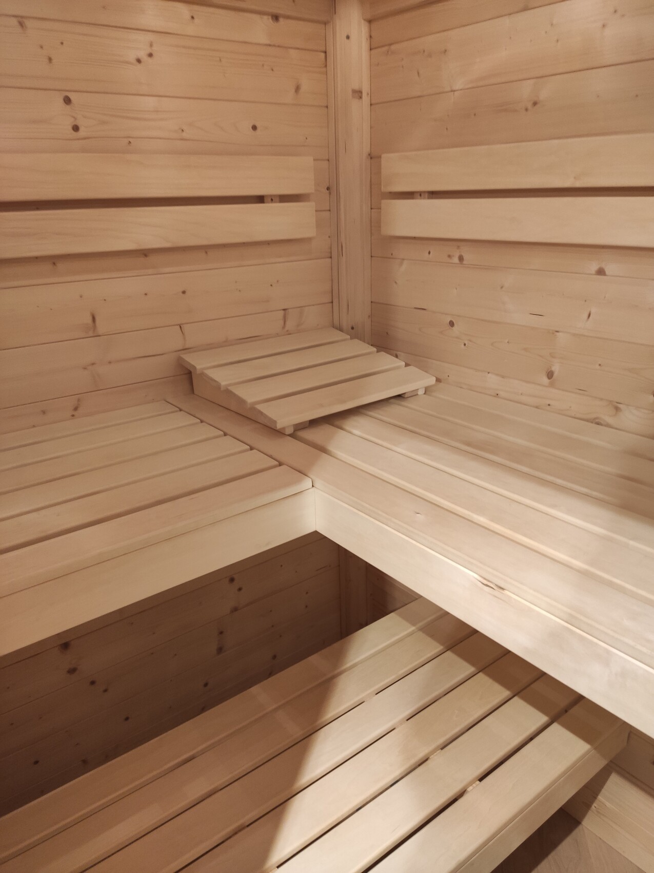 Bright wooden sauna room with multi-level benches in a corner
