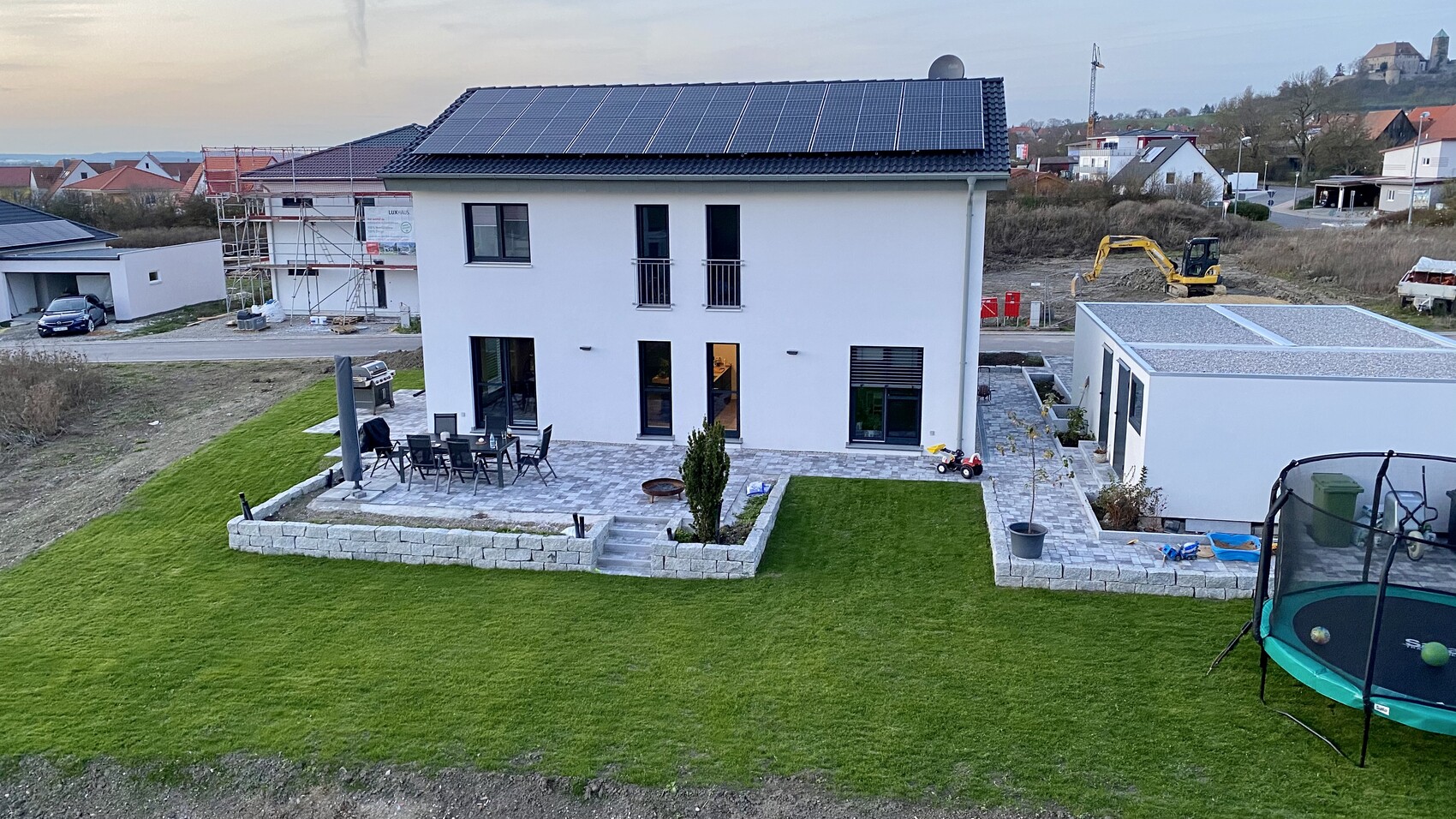 Modern two-story house with solar panel roof, terrace, and garden.