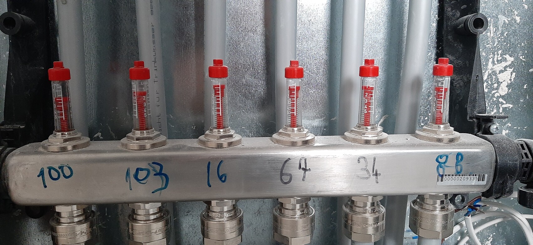 Six flow meters with red caps and liquid columns on a metal strip, numerically labeled.