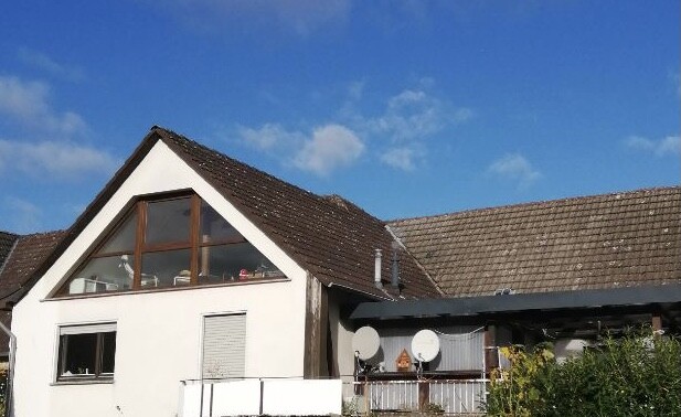 Modern house with white facade, large gable window and satellite dishes