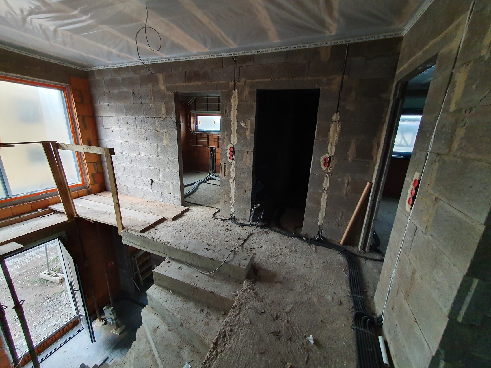 Unfinished interior of a shell construction with concrete walls, cables, and stairs