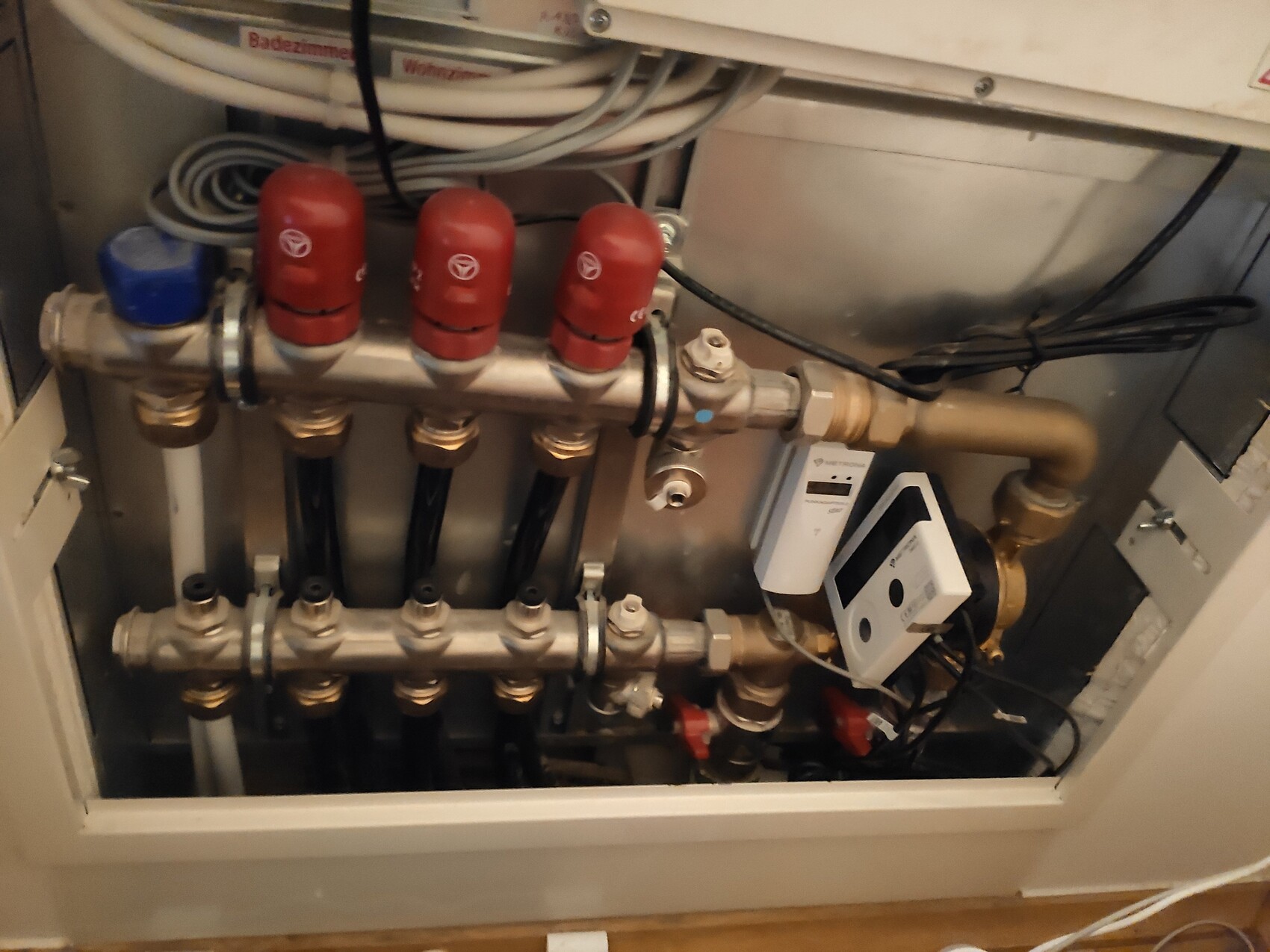 Heating distribution system with red shut-off valves, copper pipes, and electric control.