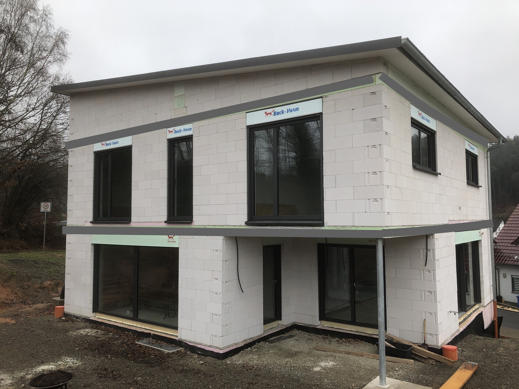 Modern two-story new build house with large window fronts at a construction site.