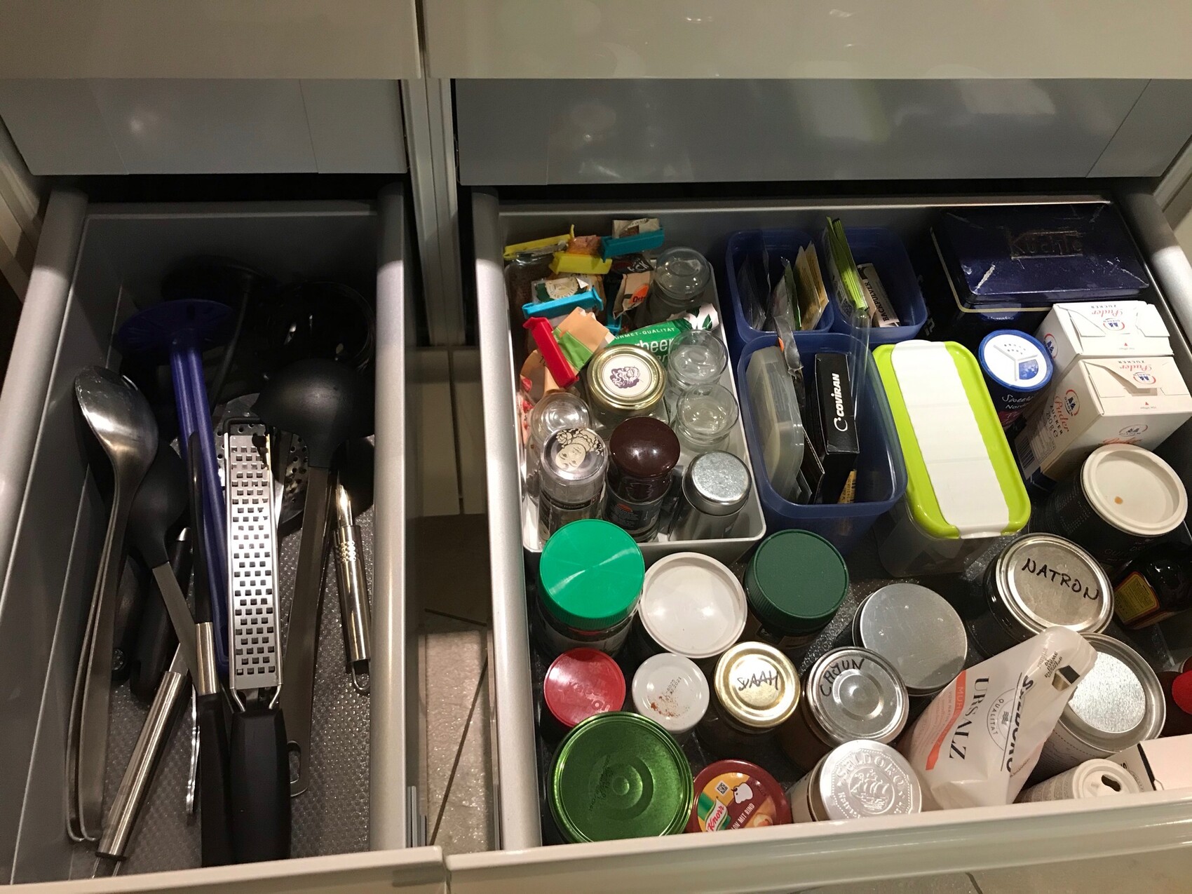 Kitchen drawer open: utensils (spoons, spatulas) on the left; jars, cans, and boxes on the right.