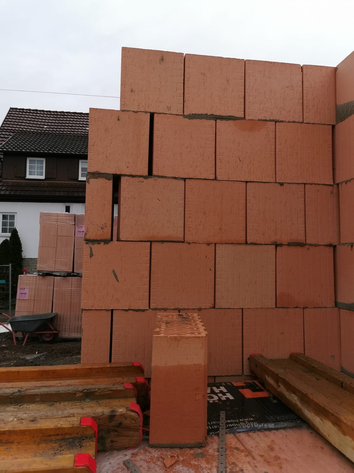 Großer Stapel orange Porenbetonblöcke auf der Baustelle, Haus im Hintergrund