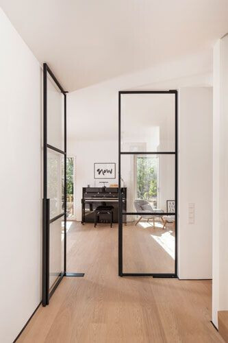Bright interior with wood flooring, black metal-framed glass sliding doors, view of a piano.