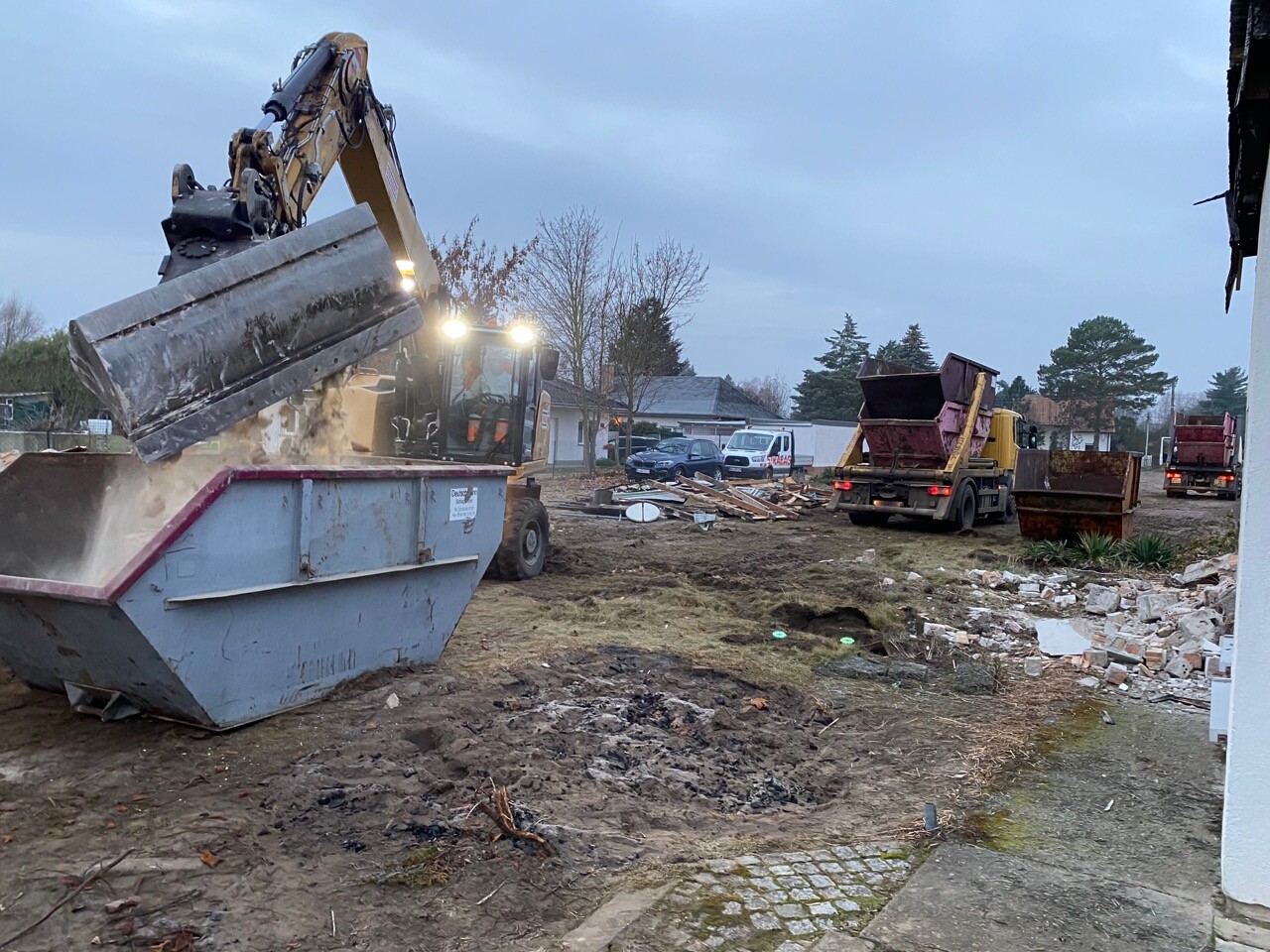 Große Baustelle mit Bagger, Muldenkippern und Schutt am Rohbaugrundstück.