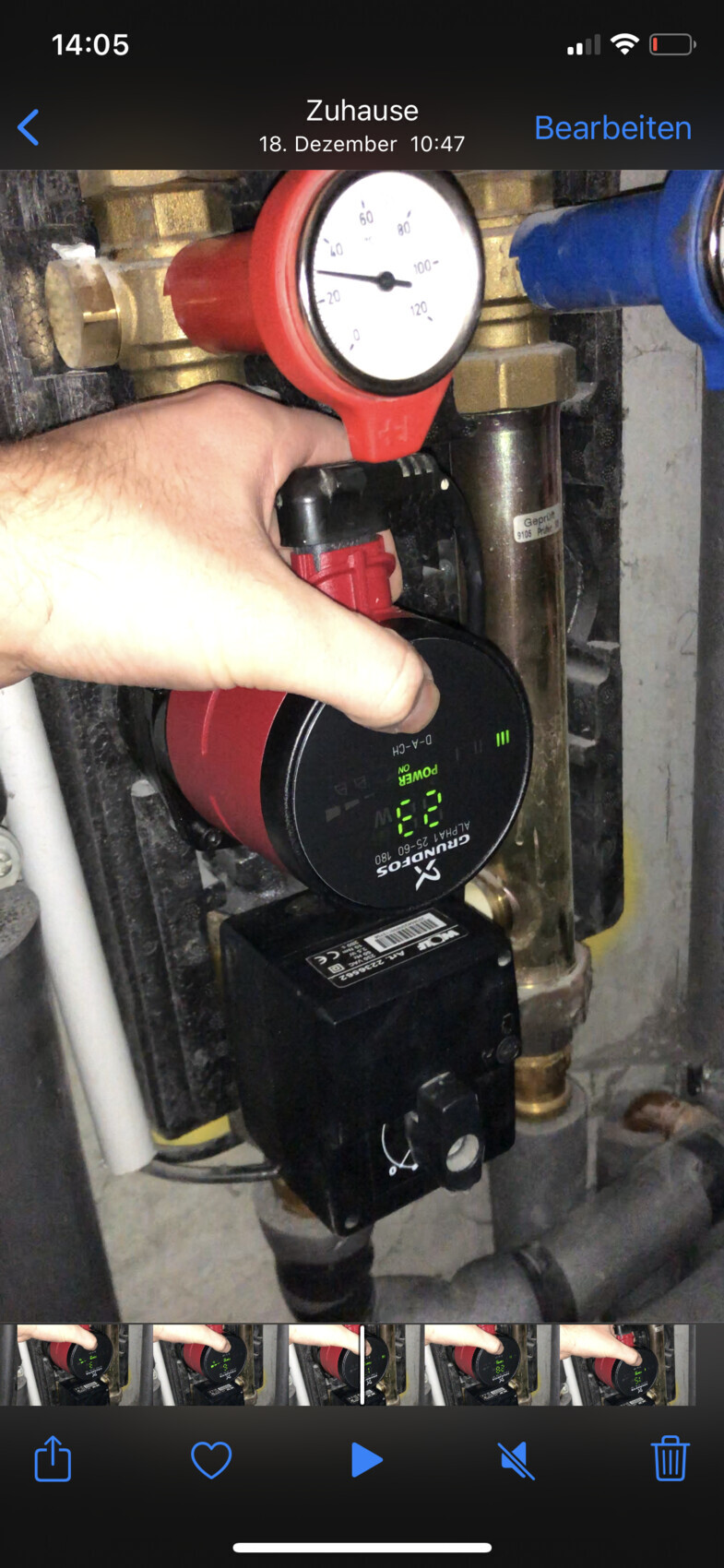 Hand operating red pump on heating system; pressure gauge showing pressure.