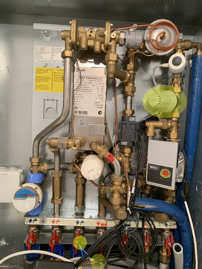 Interior view of a heating system with valves, measuring devices, pump, and control unit.
