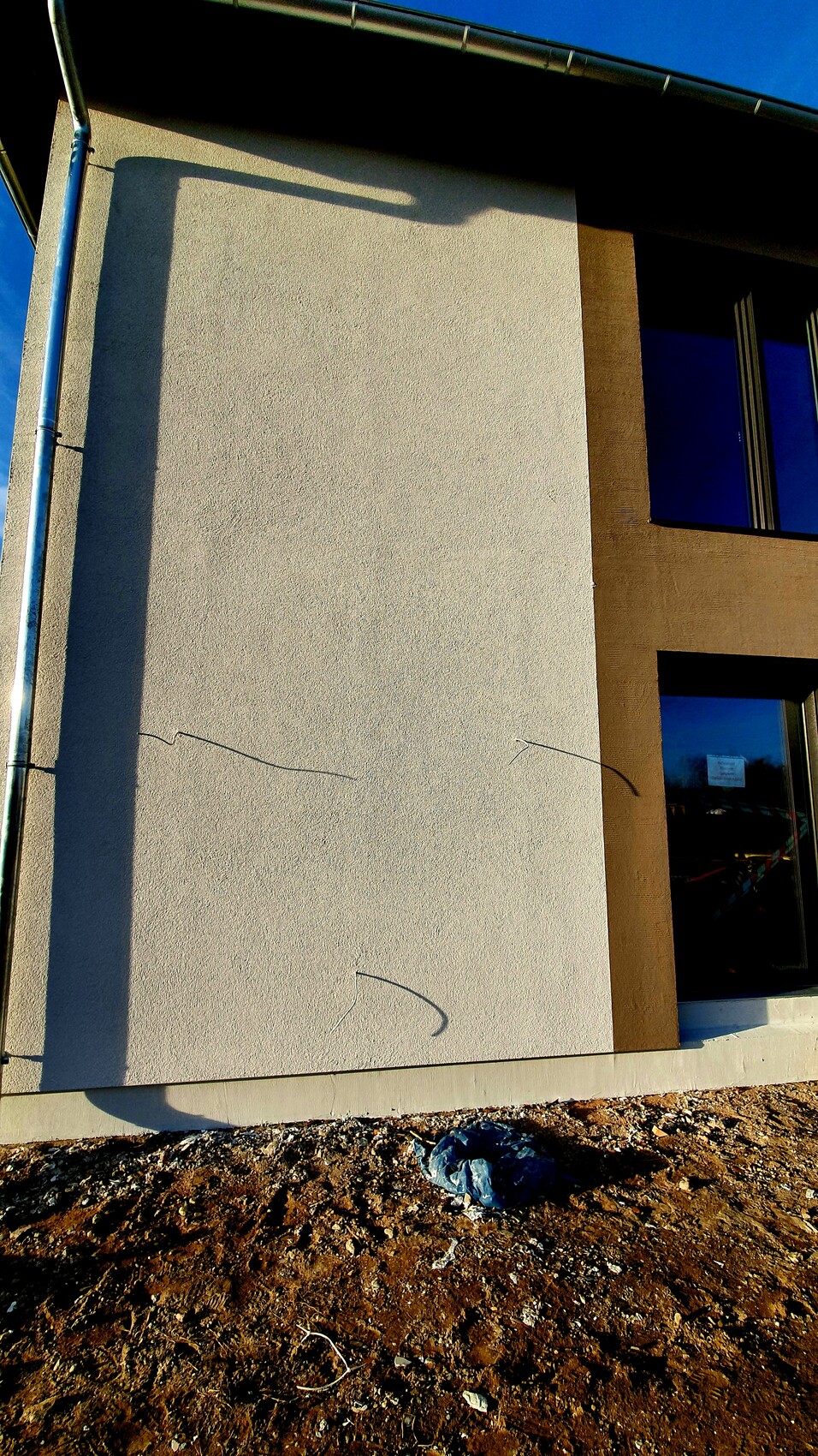 Exterior wall of a modern house facade with a window, earthworks visible