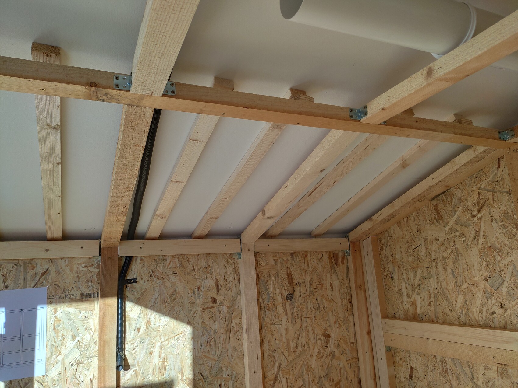 View of the shell structure: timber frame, roof beams, OSB sheathing, cable duct and piping.