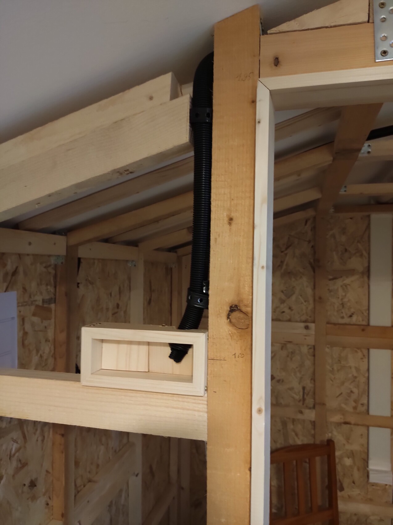 Interior construction with timber frame, black flexible cable duct and small rectangular wooden box.