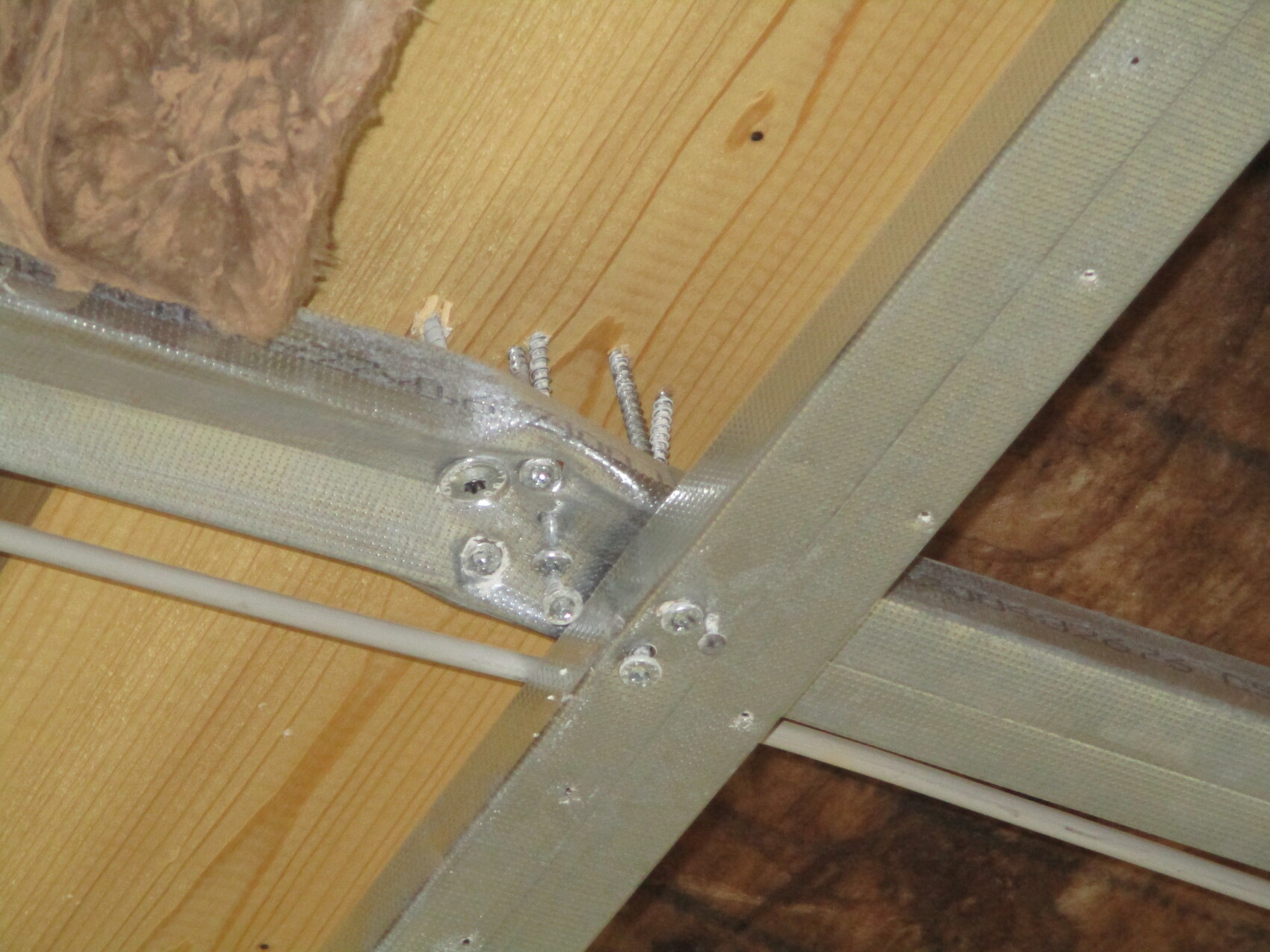 Metallrahmen aus Trägern an Holz, Schrauben sichern Verbindung; Kabelkanal sichtbar
