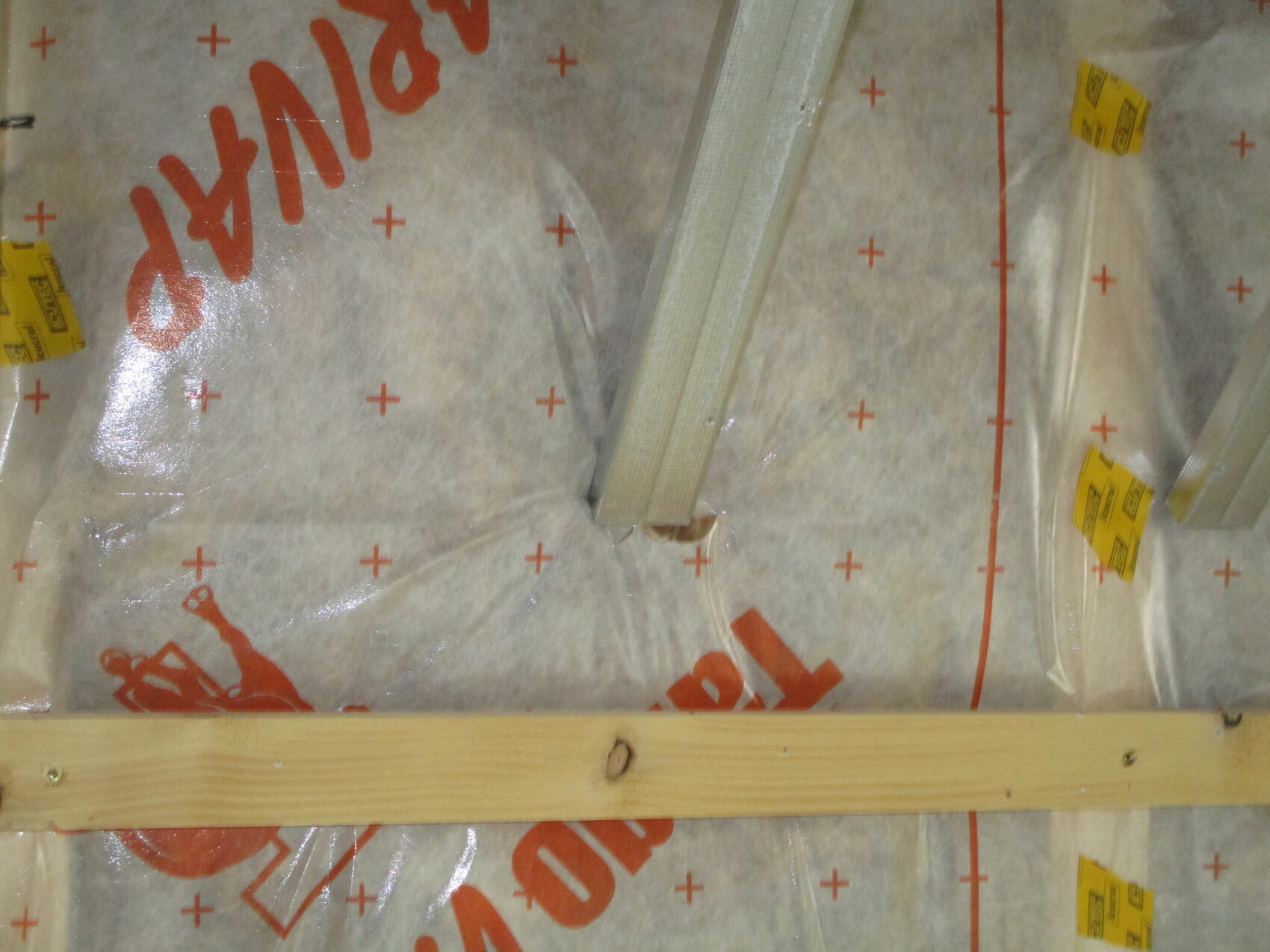 Dämmmaterial in einer Baukonstruktion, Folie mit roten Kreuzmarken und Holzlatten.