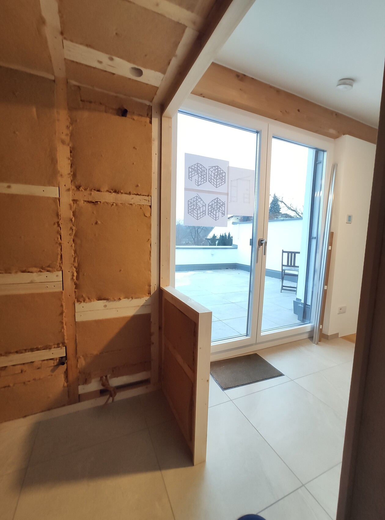 Interior under construction/renovation: exposed insulation on the wall, glass patio door