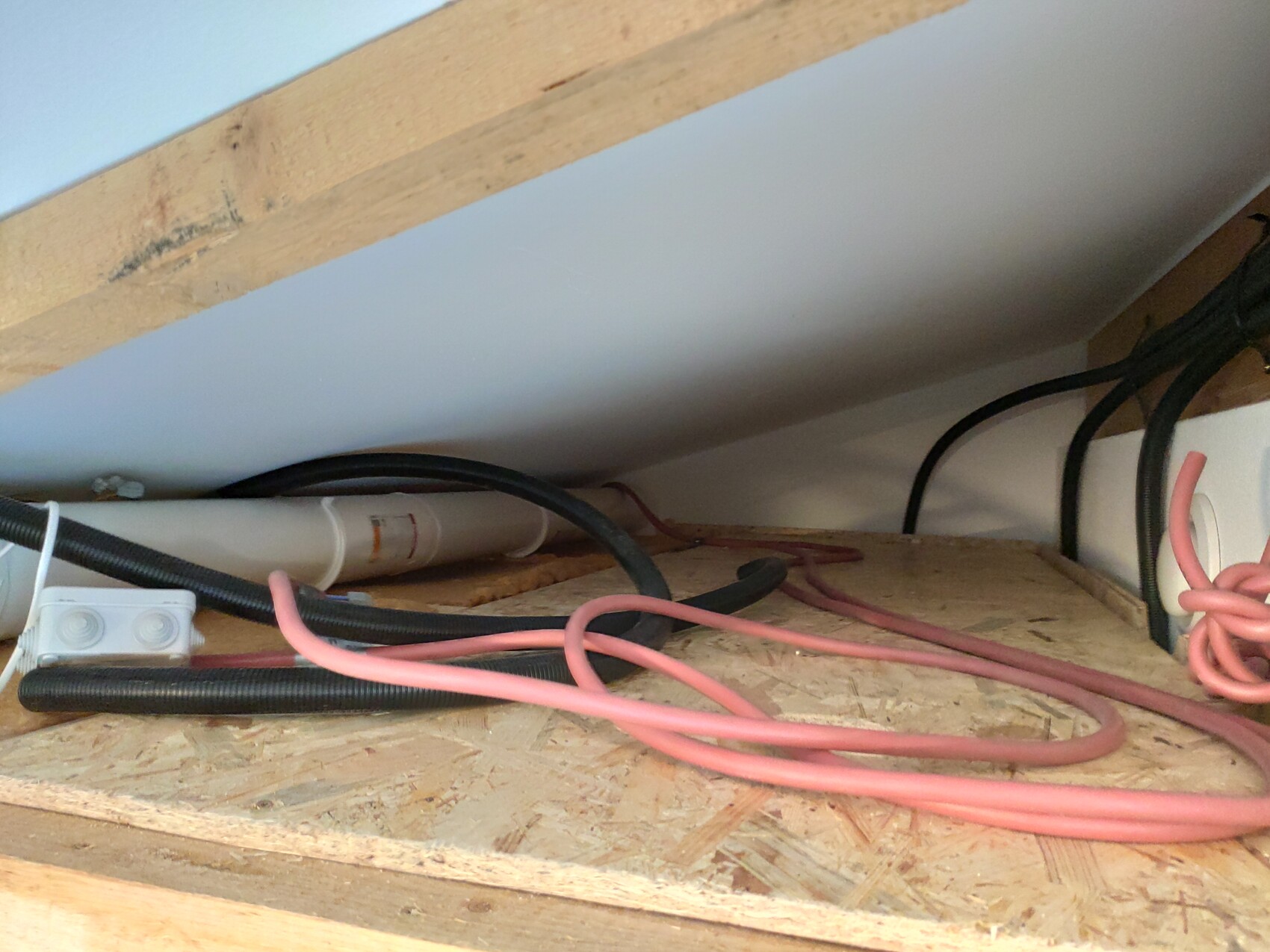 Cable clutter under sloping roof: pink power cables, black wires, PVC conduit.