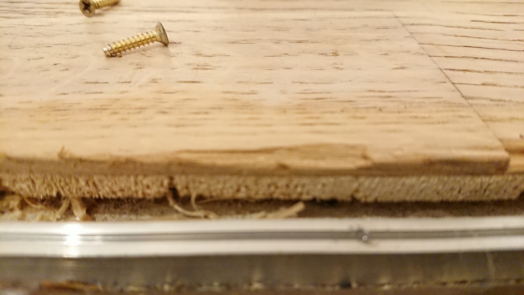 Close-up of wooden floorboards with screws on the floor.