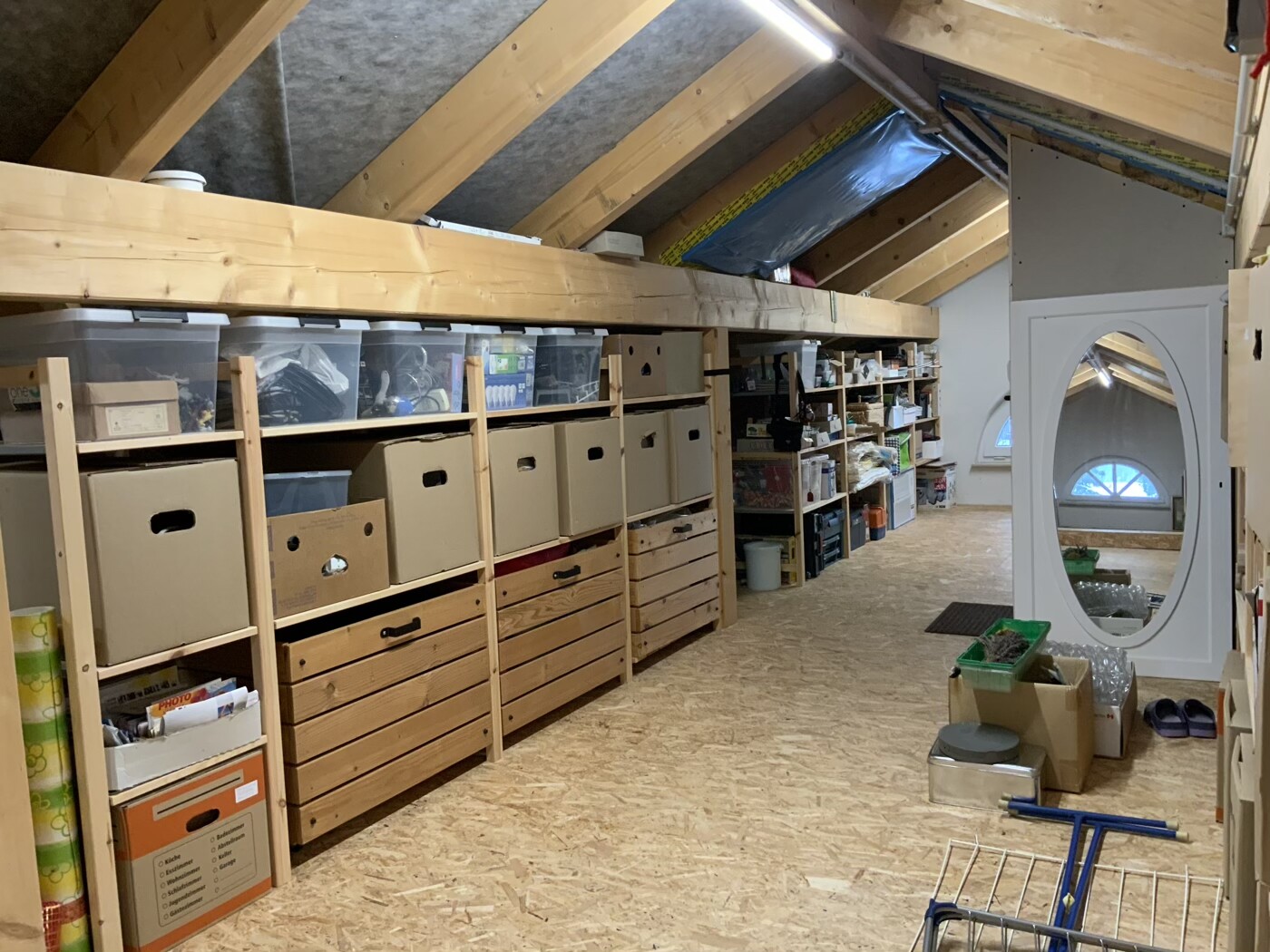 Attic: wooden shelves with cartons, boxes; white door with oval mirror.