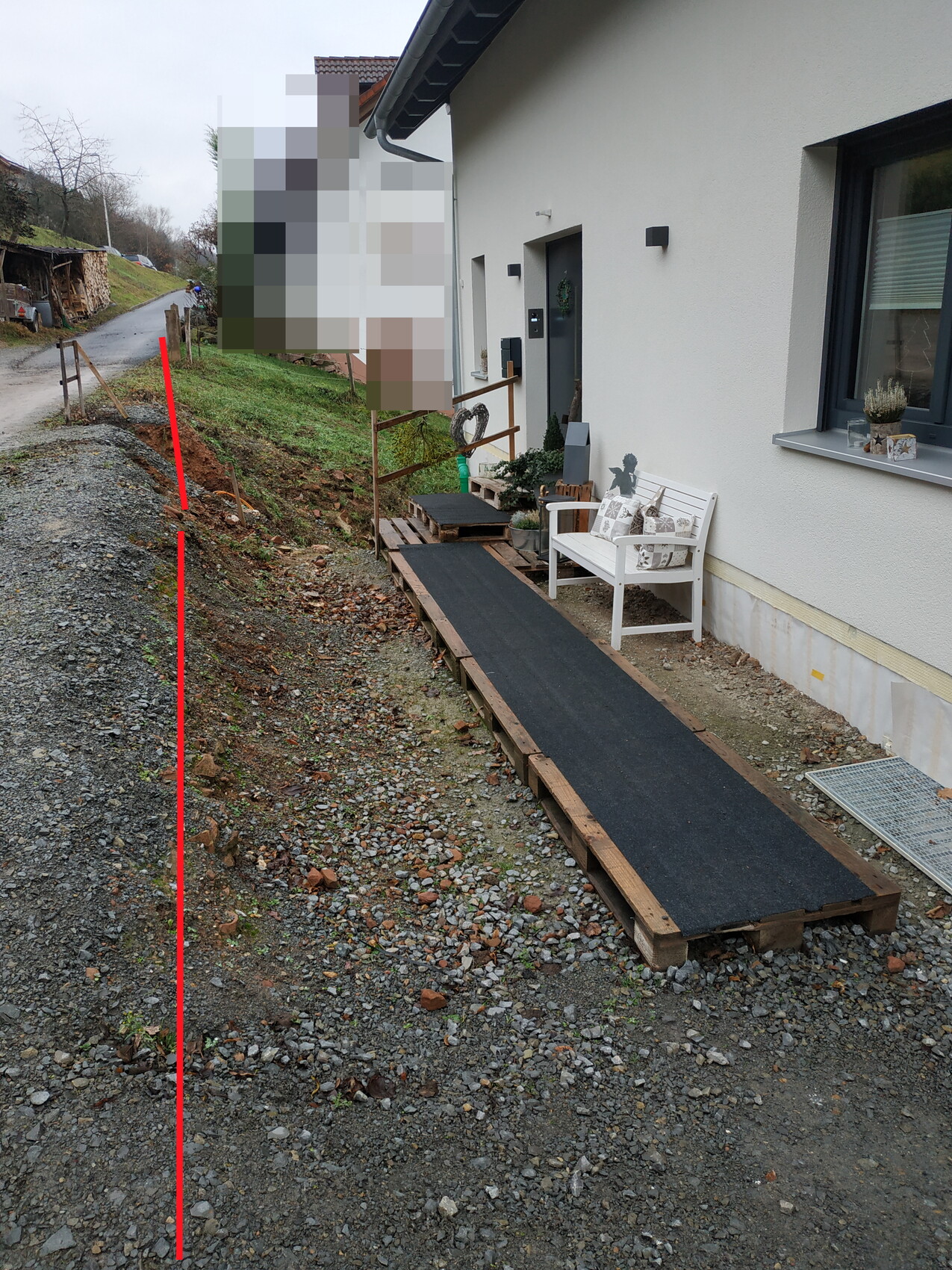 Exterior view of a house with a temporary wooden ramp and white bench in front of the entrance door.