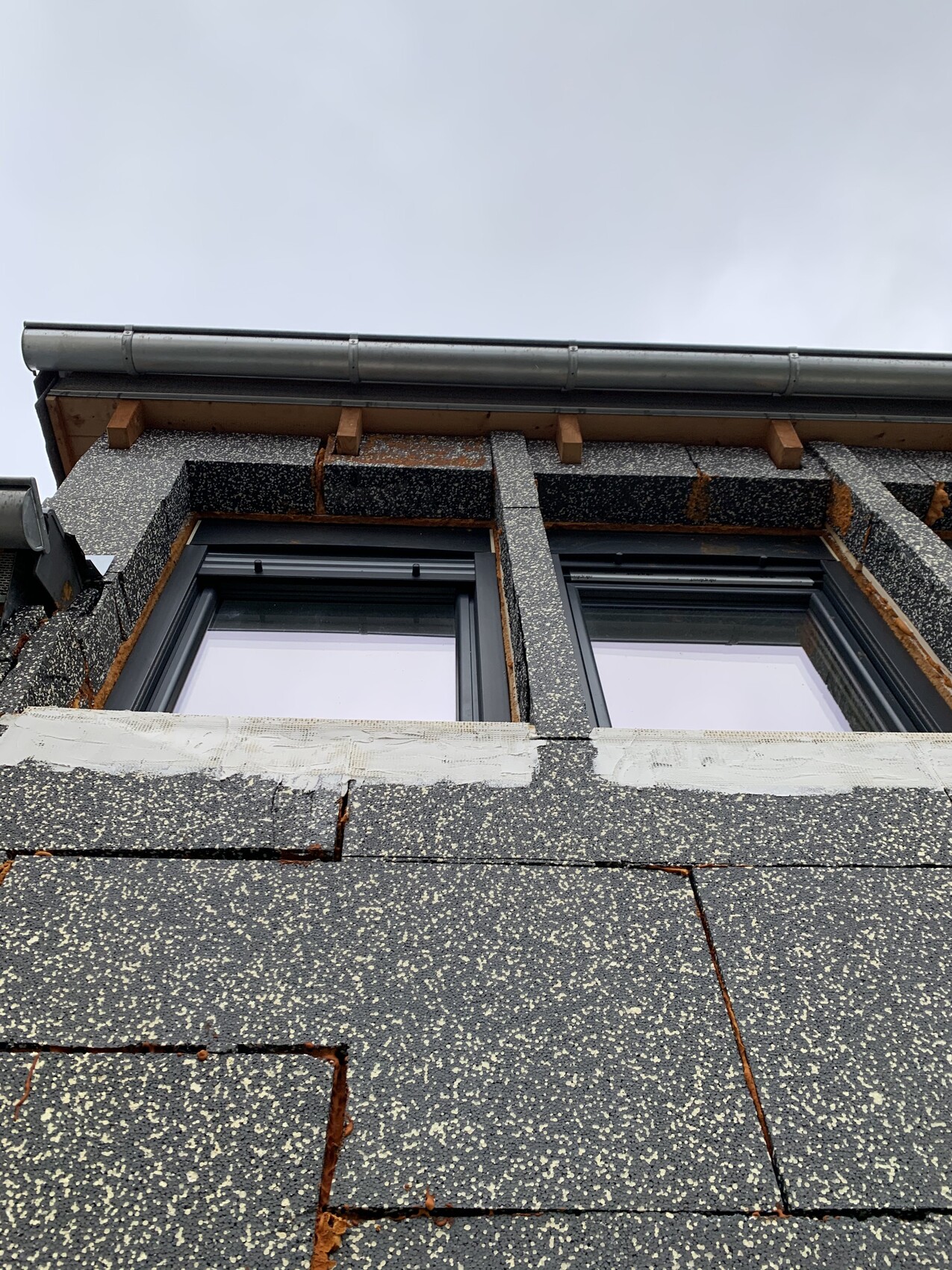 Außenansicht eines Gebäudes mit Fensterrahmen in der Fassade und Dachrinne.