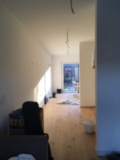Long bright interior under renovation with wooden floor, white walls and cables on the ceiling.