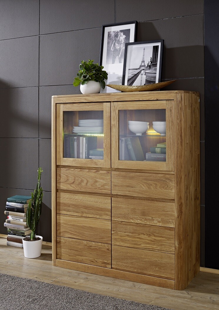 Wooden sideboard with two glass fronts, pictures, plant and bowl on top; drawers underneath.