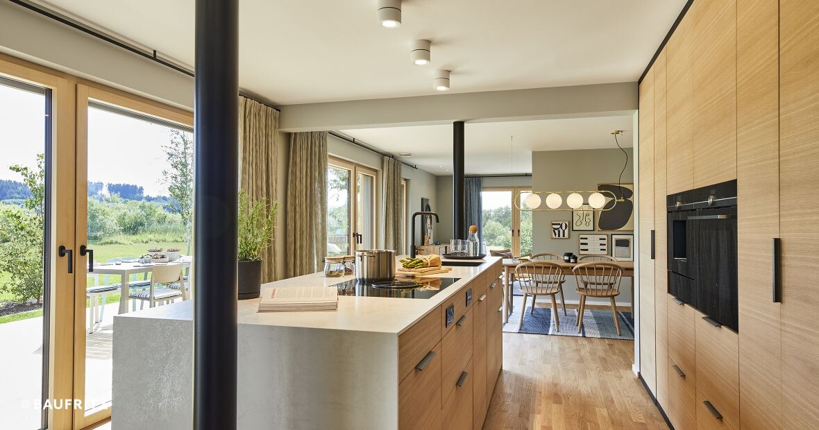 Offene Küche mit Insel, Holzmöbeln, Essbereich und Terrassenzugang zum Garten.