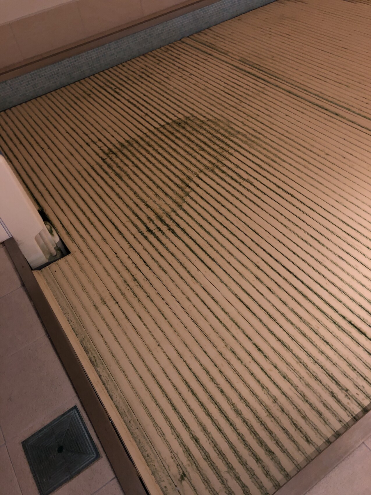 Floor with parallel wooden grooves; a large dark round stain in the middle.