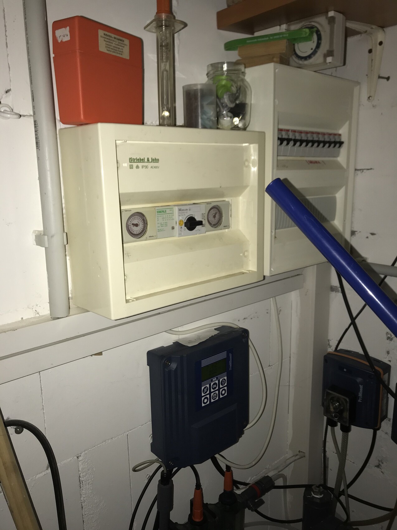 Basement room with distribution cabinets, meter, blue inverter and red fire protection box.