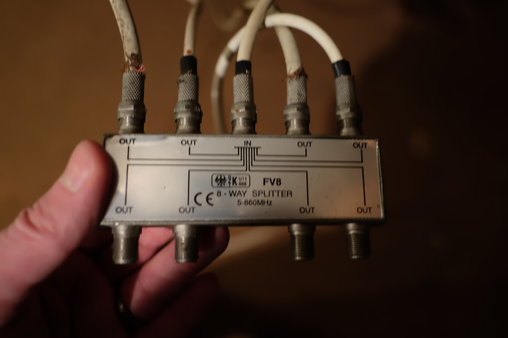 FV8 8-way splitter with eight OUT ports and cables held in hand.