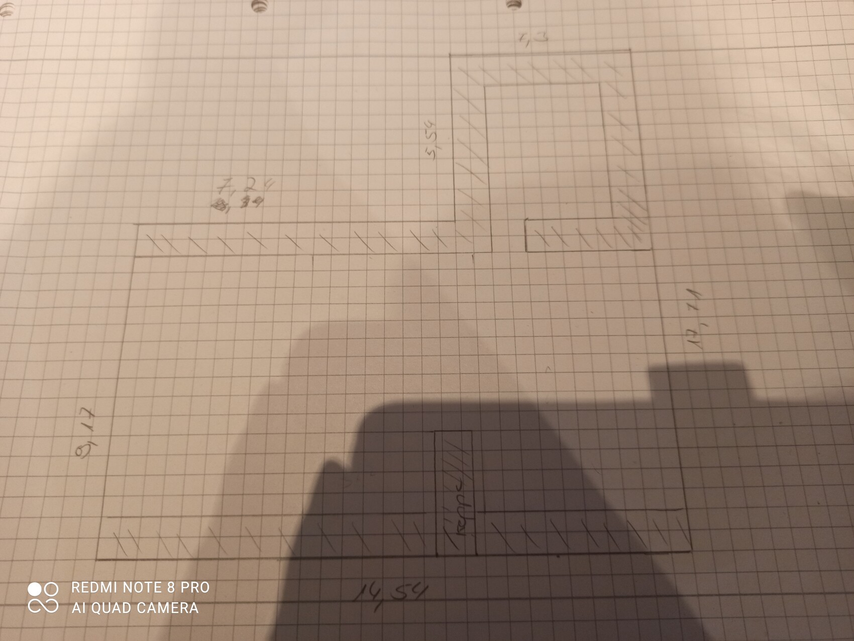 Hand-drawn floor plan on graph paper with several rectangular rooms and shaded walls.