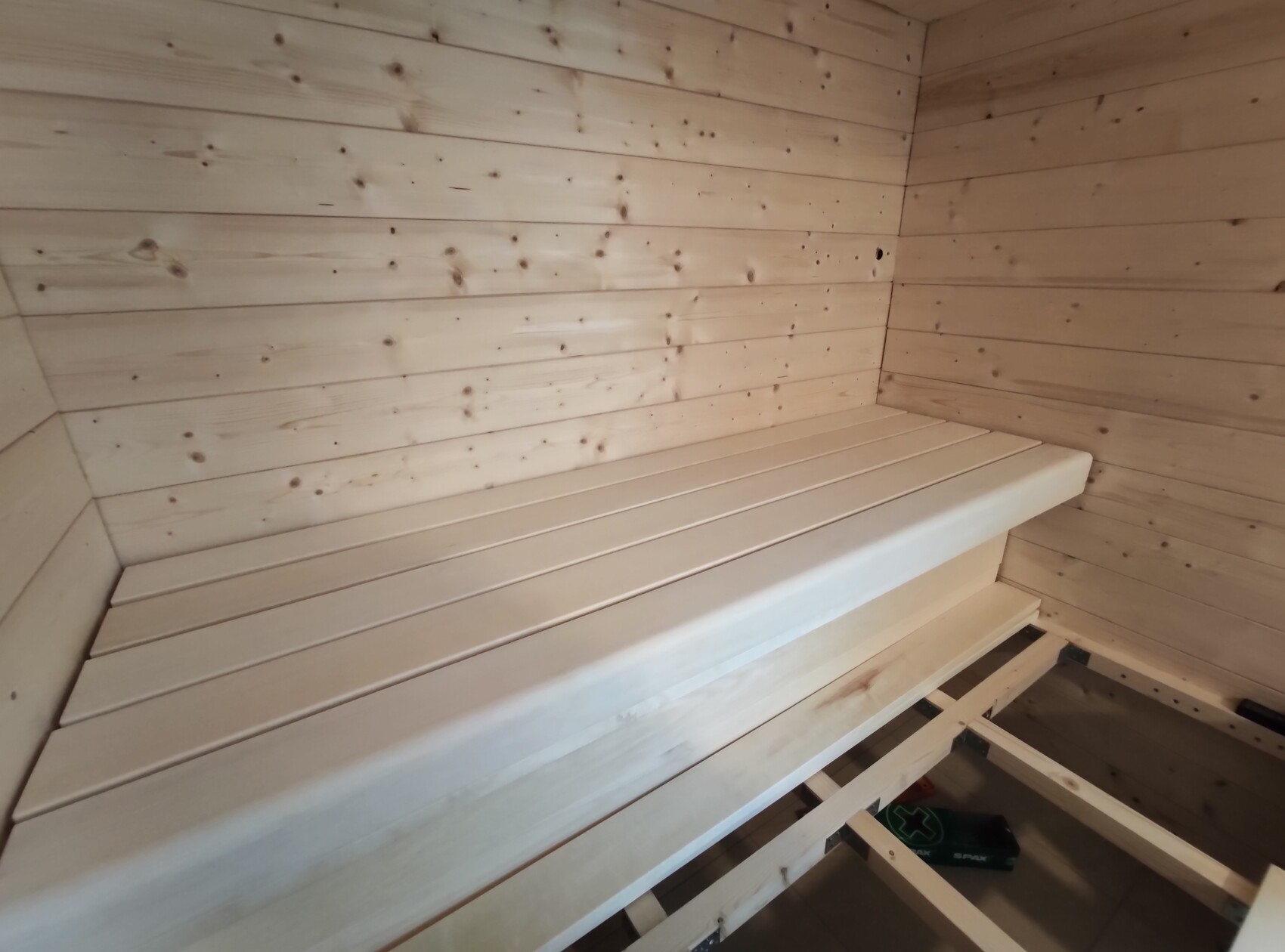 Bright wooden sauna room with a long bench along the wall and wood paneling.