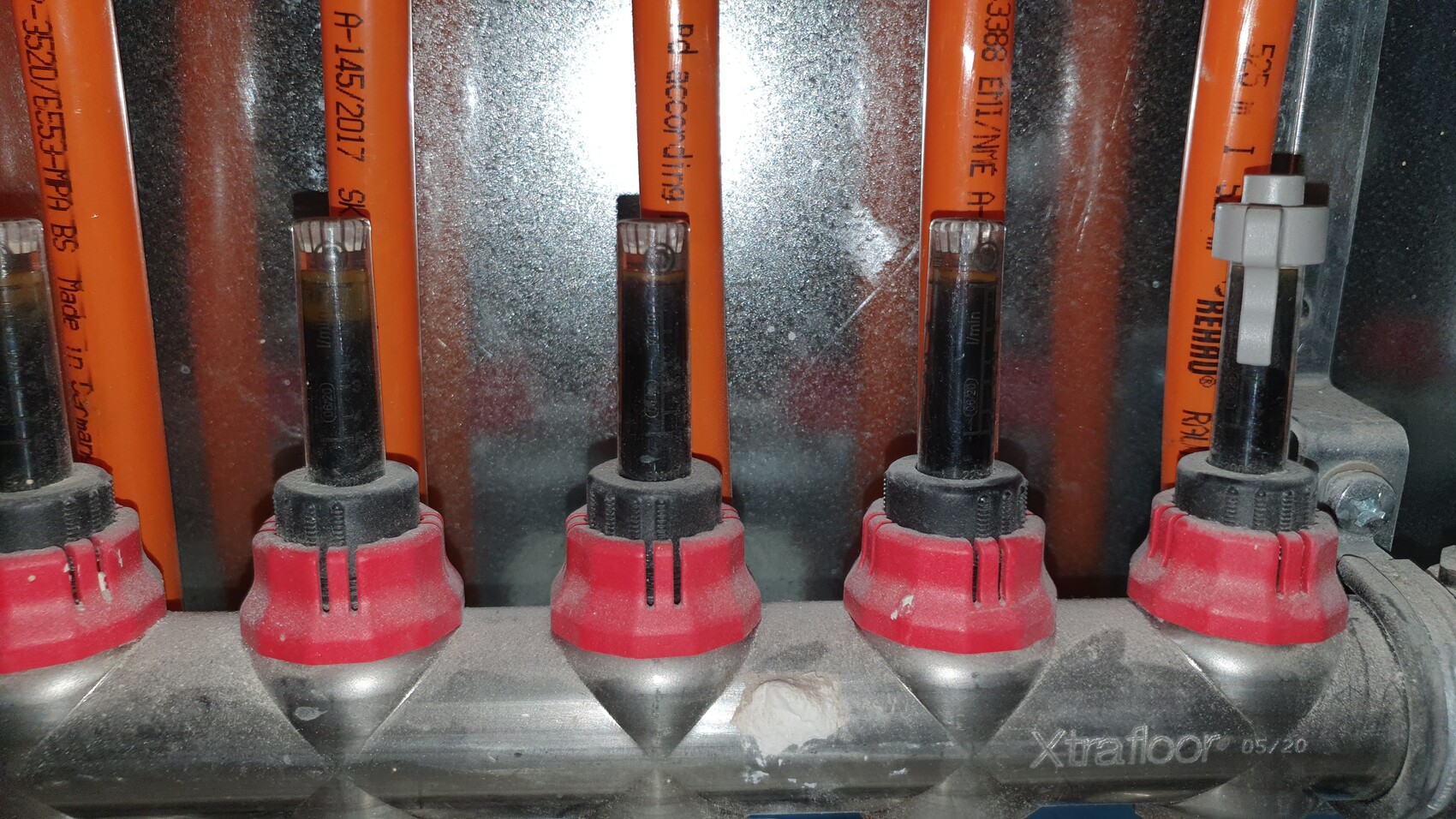 Close-up of orange cables with red caps in a dusty metal system.