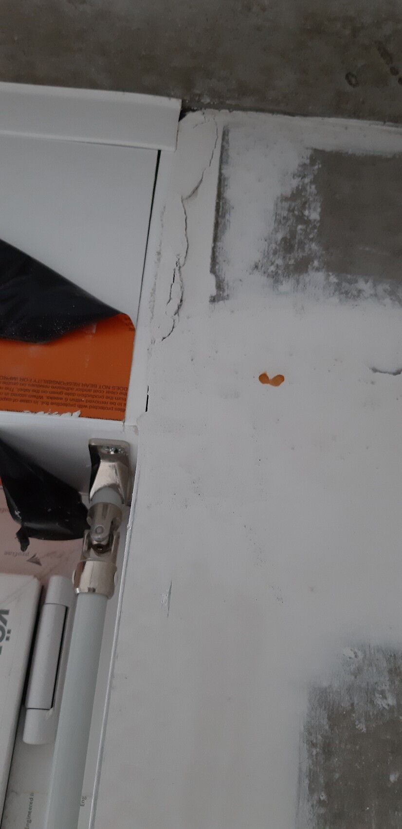 Close-up of a damaged white door frame with cracks, hinge, and open interior area.