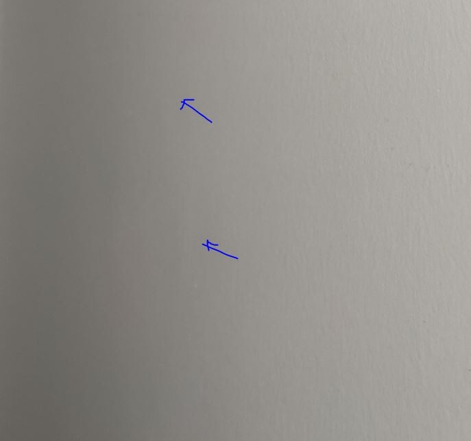 Two small blue marks on a light gray wall.
