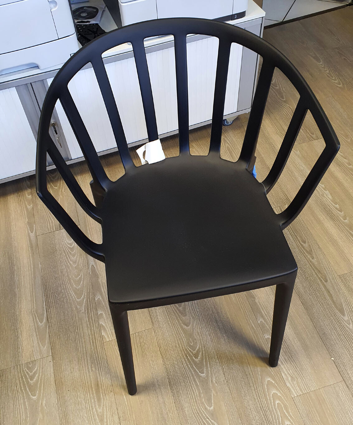 Black modern plastic chair with vertical back slats in an office