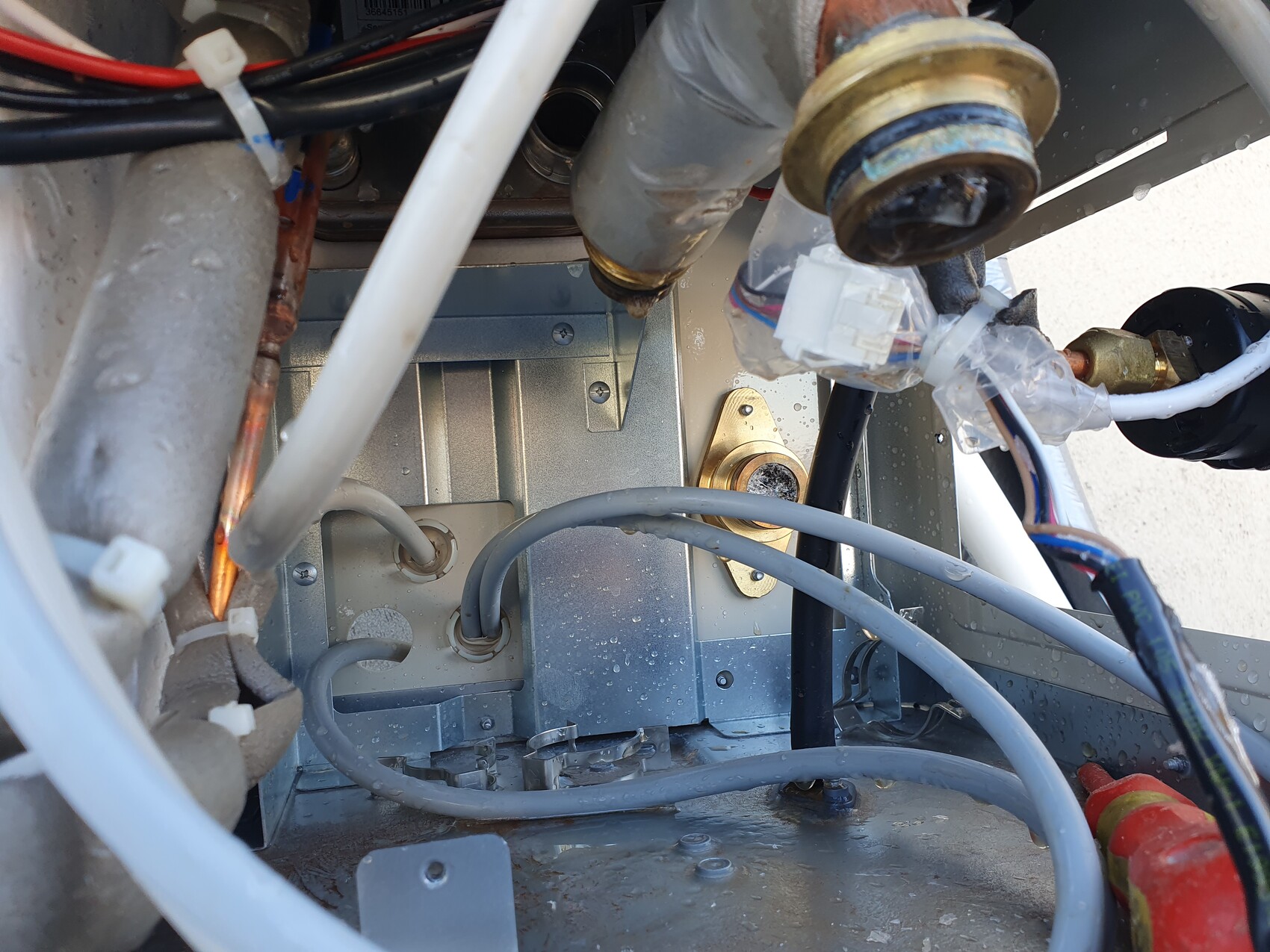 Interior view of an electrical device with cables, hoses, and metal housing.