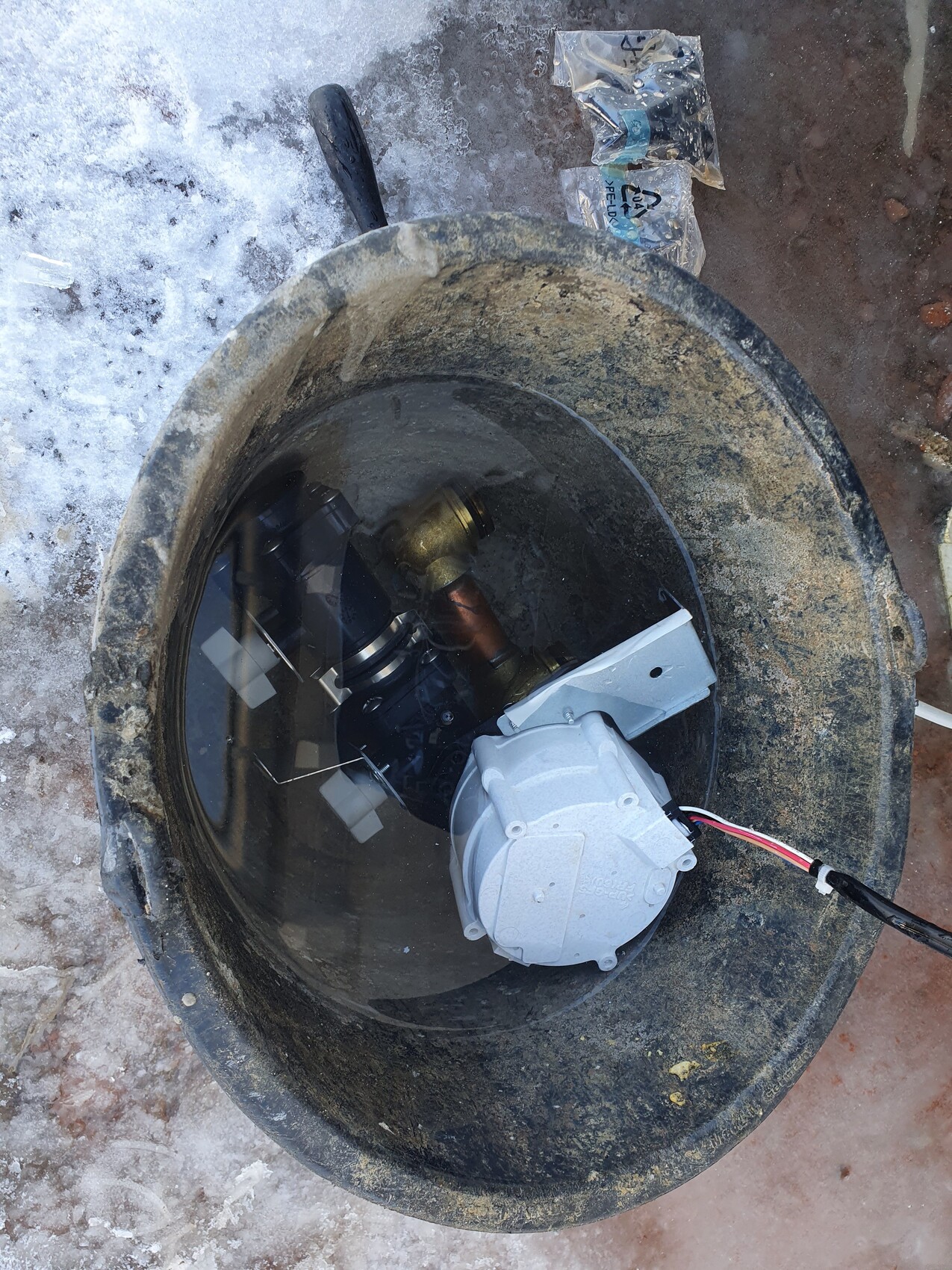 Round concrete shaft with installed submersible pump, motor housing, and cables.