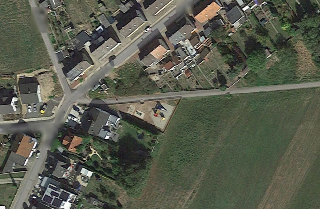 Aerial view of a settlement with an intersection, houses, and fields
